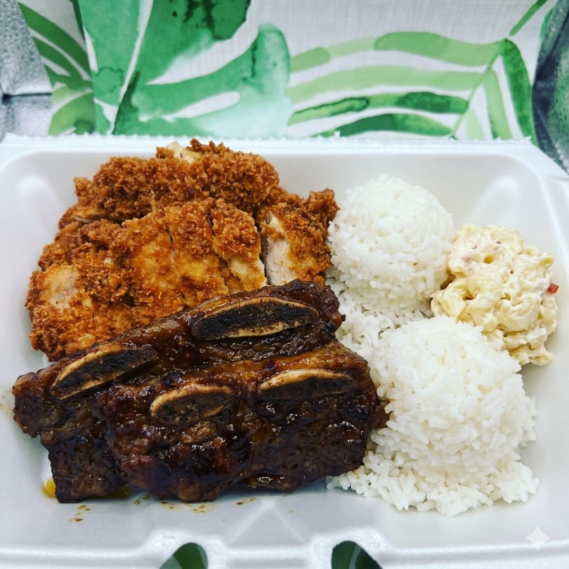 A takeout container with crispy fried chicken, saucy short ribs, white rice, and macaroni salad.