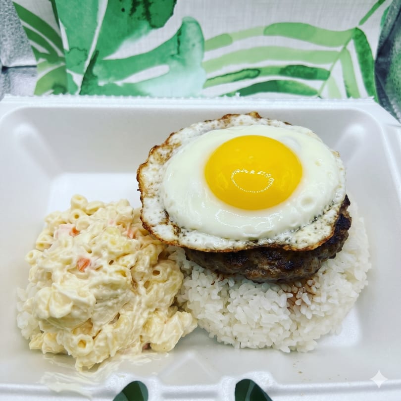 Loco Moco with a fried egg, hamburger patty, rice, and macaroni salad in a takeout container.